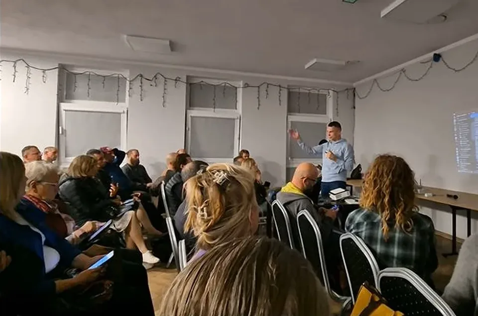 Pełna sala świetlicy w Kijanach: kilkadziesiąt osób na krzesłach słucha prelegenta, na ścianie po prawej obraz z projektora